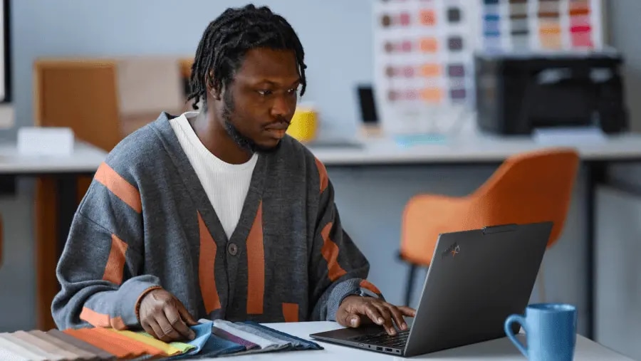 一位男子坐在桌前，正在使用 Lenovo ThinkPad X1 筆記型電腦看色彩樣板。