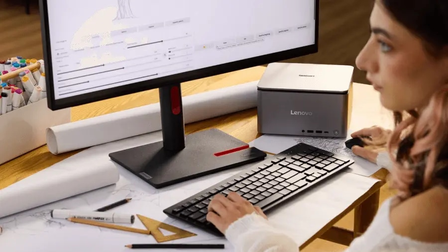 專心使用 ThinkCentre 桌上型電腦的一位人士，其臉部的近距離裁剪視圖，桌上散落著各種建築圖紙和工具。