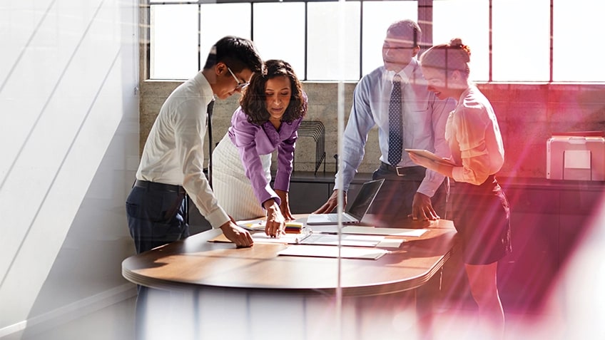 五人圍坐在會議室桌旁，看著 Lenovo 筆記型電腦。